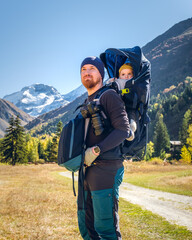 Father on a hiking trip with the 8 months old baby in a baby carrier