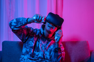 Young man wearing virtual reality (VR) glasses and uses joystick to play games with fun playing games in a room with red and blue lights, 3D game, Future games, Gadgets, Technology, Game concept