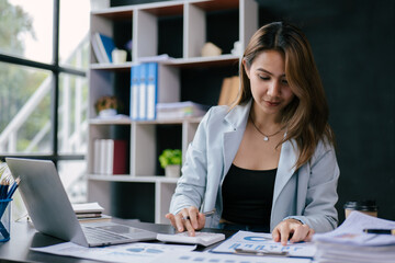 Young business women working and calculating on laptop with happy and smile face on office spec.