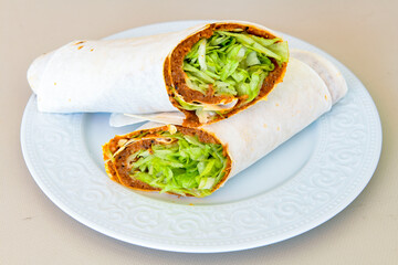Cig kofte (raw meatball) with lettuce, tomato, pickle and lemon, hot Chee kofta. Turkish local raw food concept.Table scene of assorted take out or delivery foods. Doritoslu cig kofte durum.