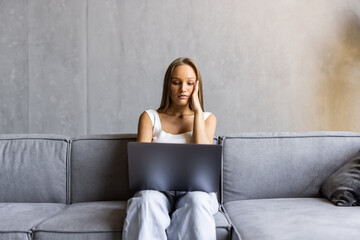 Frustrated sad woman feeling tired worried about problem sitting on sofa with laptop, stressed...