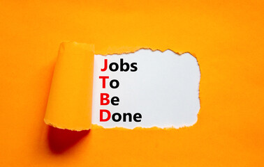 JTBD jobs to be done symbol. Concept words JTBD jobs to be done on white paper on a beautiful orange background. Business and JTBD jobs to be done concept. Copy space.