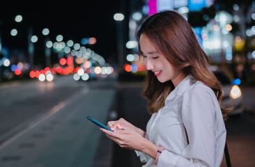 Charming Asian businesswoman use mobile phone in the city at night