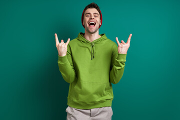 Handsome young man gesturing and smiling while standing against green background