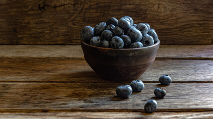 Blueberries in a clay cup, on a wooden table. Ripe berries in the kitchen, harvest.