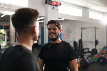 Fototapeta na wymiar Two personal trainers smiling at each other at their workplace in the crossfit box