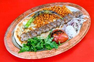Grilled Turkish Adana, Urfa  Kebab with grilled vegetables, onion and rice on plate. Adana durum .