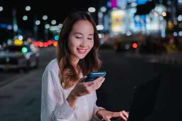 Charming Asian businesswoman use mobile phone in the city at night