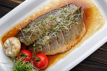 Dorado fish fillet grilled in sauce, with tomatoes