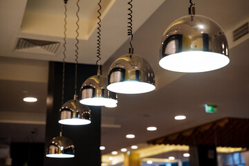Lighting in the restaurant, a shiny ball of a chandelier hanging from a shelf, designer lamps, a...