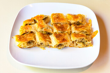 Turkish style meat stuffed filo dough borek served kol boregi. Cheese and minced pie are sliced on a marble background. Turkish name: Kol Boregi, kiymali, peynirli su boregi.