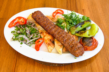 Grilled Turkish Adana, Urfa  Kebab with grilled vegetables, onion and rice on plate. Adana durum .