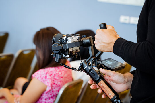 Shooting process from hand to camera, a person shoots an event holding steadicam in his hands, a device that balances the camera, an image stabilizer.