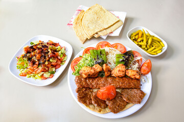 Grilled Turkish Adana, Urfa  Kebab with grilled vegetables, onion and rice on plate. Adana durum .