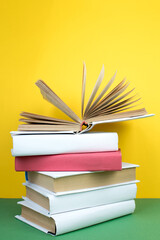 Fototapeta premium Book stacking. Open hardback books on wooden table and green background. Back to school. Copy space for ad text.