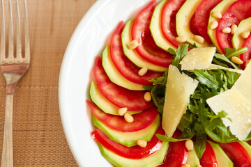 Dietary salad with zucchini, tomato, arugula and sliced parmesan.