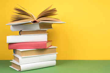 Book stacking. Open hardback books on wooden table and green background. Back to school. Copy space for ad text.