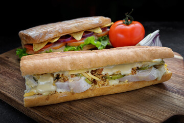 Sandwich with meat, cheese and cucumbers on a wooden board