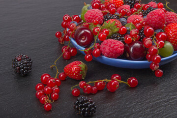 Various summer Fresh berries in a bowl on rustic wooden table. Antioxidants, detox diet, organic fruits.