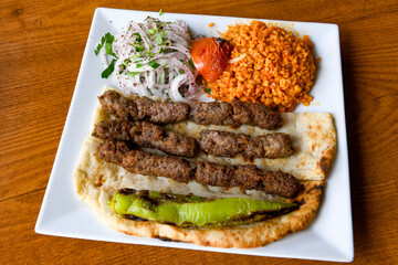 Grilled Turkish Adana, Urfa  Kebab with grilled vegetables, onion and rice on plate. Adana durum .