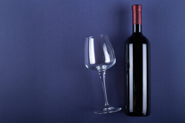 Bottle of red wine without a label and a glass empty on a purple paper background. Mockup drink with place for you label and text. Space for text.