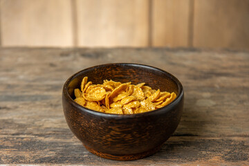 Cereal in wooden bowl with milk splash on blurred wooden