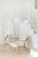 Modern wooden lounge chair with floor lamp and stylish oval full length mirror in white living room...