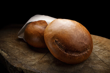 Obraz premium Dark round bread on a wooden board