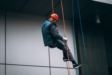 Industrial climber in uniform and helmet rises