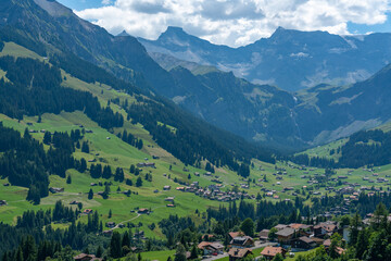 Obraz premium Adelboden im Panorama, Bergdorf mit vielen schönen und alten Holzhäusern, Bergwiesen, Wäldern und den hohen Bergen Grosser Lohner und Wildstrubel im Hintergrund. Streusiedlung im Engstligental. 