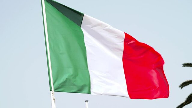 Italian flag wave in the wind on flagpole against the sky.
