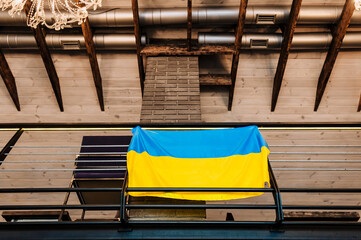 Ukrainian large yellow-blue fabric flag hangs indoors, in the interior against the background of the wall. Photography, Ukraine.