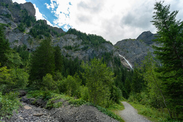 Wasserfall im Tal von Adelboden, weithin sichtbar über den Bäumen. Engstligenfälle am Talende. immer weniger Wasser kommt vom Gletscher auf der Engstligenalp den Wasserfall herunter