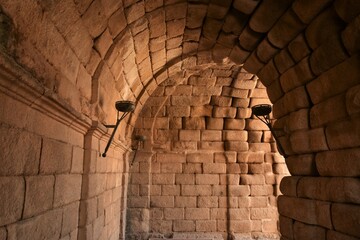 Barrel vaulted access tunnel to Merida Roman theatre, lined by elegant sandstone blocks and iron torches still amazes by serene simplicity 2000 years after construction, Mérida, Spain - obrazy, fototapety, plakaty