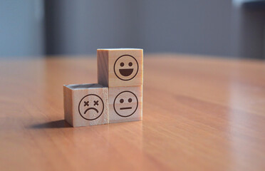 Emoji faces with smile, neutral, sad face expressions on blocks on a table - Happy, happyness, sad,...