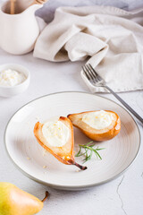 Baked pears with ricotta, nuts, honey and rosemary on a plate. Homemade dessert. Vertical view
