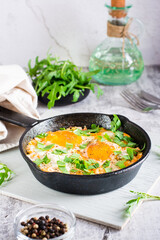 Shakshuka with tomatoes and arugula in a pan. Traditional mediterranean dish. Vertical view
