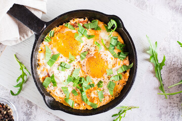 Shakshuka with tomatoes and arugula in a pan. Traditional mediterranean dish. Top view. Close-up