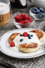 Cottage cheese pancakes with blueberries and raspberries and sour cream.