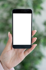 Virtual work. Digital mockup. Mobile connection. Unrecognizable woman holding smartphone with blank screen in light room interior.