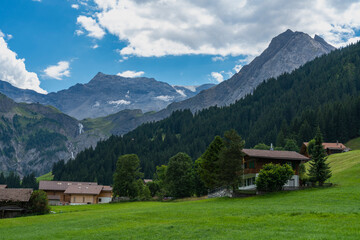 Obraz premium alte Bauernhäuser aus Holz im Boden, Adelboden. Streusiedlung mit Wiesen und Wäldern in den schweizer Alpen. Berge im Hintergrund