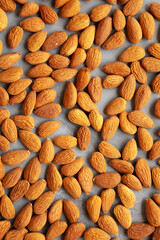 Raw brown almonds on a gray background, top view. Flat lay, overhead, from above.