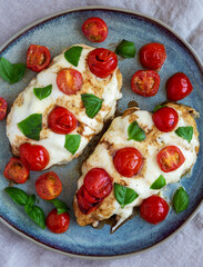 Homemade Caprese Chicken Parmesan with tomato, mozzarella and basil on a Plate, top view. Flat lay, overhead, from above.