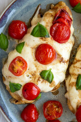 Homemade Caprese Chicken Parmesan with tomato, mozzarella and basil on a Plate, top view. Flat lay, overhead, from above. Close-up.