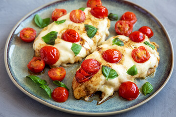 Homemade Caprese Chicken Parmesan with tomato, mozzarella and basil on a Plate, side view.