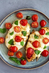 Homemade Caprese Chicken Parmesan with tomato, mozzarella and basil on a Plate, top view. Close-up.