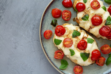 Homemade Caprese Chicken Parmesan with tomato, mozzarella and basil on a Plate, top view. Space for text.