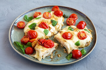 Homemade Caprese Chicken Parmesan with tomato, mozzarella and basil on a Plate, side view. Close-up.