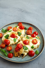 Homemade Caprese Chicken Parmesan with tomato, mozzarella and basil on a Plate, side view. Copy space.