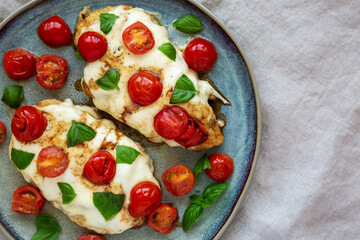 Homemade Caprese Chicken Parmesan with tomato, mozzarella and basil on a Plate, top view. Flat lay, overhead, from above. Copy space.
